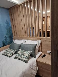 1 dormitorio con cama con cabecero de madera y almohadas en Apartman 318 - Sunčana Planina, en Kopaonik