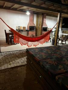 a hammock in a room with a table and a fireplace at Pousada Vielas do Rosa - centrinho da praia do rosa in Praia do Rosa