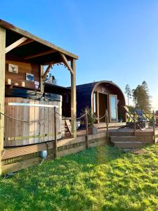 ein Holzhaus mit einem Zaun und Gras in der Unterkunft FINN VILLAGE – Loch Lomond Luxury Lodges with All Year-Round Hot Tubs and Gazebos in Glasgow