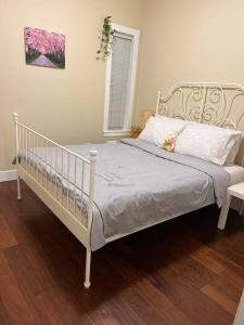1 cama blanca en un dormitorio con suelo de madera en Private Guest Suite With Backyard, en Burnaby