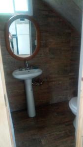 een badkamer met een spiegel, een wastafel en een toilet bij Arriba y La escondida in Villa Gesell