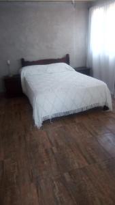 um quarto com uma cama branca e piso em madeira em Arriba y La escondida em Villa Gesell