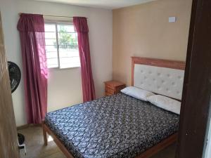 a bedroom with a bed and a window with red curtains at Cabañas Hawai in Villa Parque Siquiman