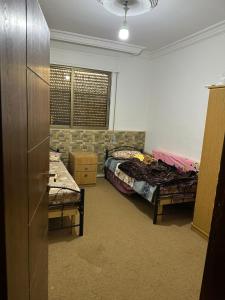 伊爾比德的住宿－شقه للأيجار في منطقه الراهبات الورديه，一间设有两张床的房间和一间带两张桌子的房间