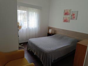 ein Schlafzimmer mit einem Bett und einem Stuhl und einem Fenster in der Unterkunft Casa El Ceibo Reserva con Seña in Piriápolis
