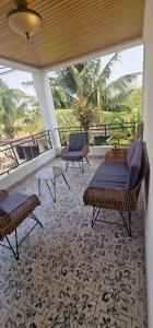 einen Balkon mit Stühlen, Tischen und einer Palme in der Unterkunft Greystone Mansion in Accra