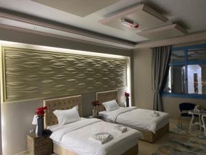 Bareen Hotel في عجمان: غرفة نوم بسريرين ولوحة كبيرة على الحائط