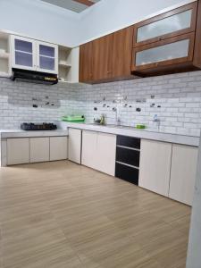 - une cuisine avec des comptoirs blancs et des armoires en bois dans l'établissement Villa Brastagi Gunung Mas Blok A1, à Berastagi