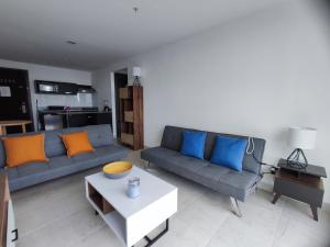 salon z 2 niebieskimi kanapami i stołem w obiekcie Playa Coronado, Apartamentos con vista al mar w mieście Las Lajas