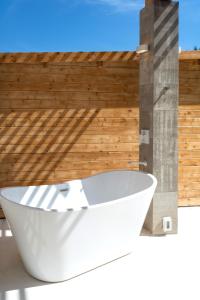 una vasca da bagno bianca di fronte a una parete in legno di Casa SANA a Puerto Escondido