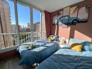 a bedroom with two beds and a window with a car on the wall at Karola cosy in Benidorm