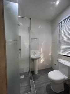 a white bathroom with a toilet and a sink at Oluyole Apartments Ibadan in Ibadan