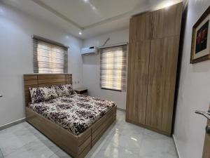 イバダンにあるOluyole Apartments Ibadanのベッドルーム1室(ベッド1台付)、木製キャビネットが備わります。