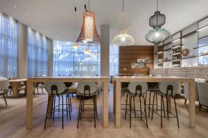 a dining room with a large wooden table and stools at AC Hotel Som by Marriott in Hospitalet de Llobregat