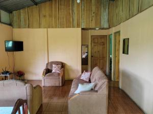 uma sala de estar com dois sofás e uma televisão em Bella Vista Guest house em Turrialba