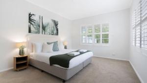 a white bedroom with a large bed and two windows at Adelong in Kiama Downs