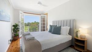 a bedroom with a large bed and a large window at Adelong in Kiama Downs