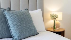 a bed with a blue pillow and a vase of flowers on a table at Adelong in Kiama Downs