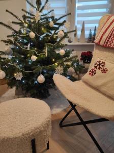 Apartment RAMUŁTA 53 Gdynia balcony Netflix PS4 في غدينيا: شجرة عيد الميلاد في غرفة معيشة مع كرسي