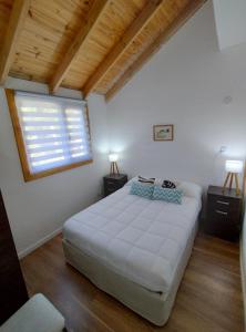 - une chambre avec un grand lit blanc et une fenêtre dans l'établissement Playa Serena, à San Carlos de Bariloche