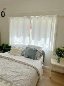 a bedroom with a large bed with white curtains at three bedroom house within walking distance to light rail station in Sydney