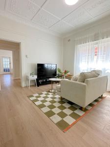 uma sala de estar com um sofá e uma televisão em three bedroom house within walking distance to light rail station em Sydney