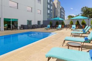 a swimming pool with lounge chairs and a hotel at Courtyard by Marriott San Jose Airport Alajuela in Alajuela City