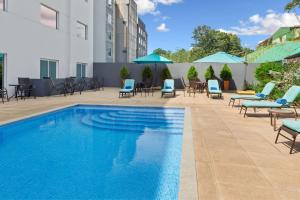 a pool at a hotel with chairs and umbrellas at Courtyard by Marriott San Jose Airport Alajuela in Alajuela City