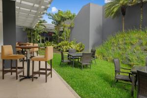 a patio with tables and chairs on the grass at Courtyard by Marriott San Jose Airport Alajuela in Alajuela City
