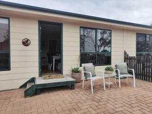 eine Terrasse mit Stühlen, einem Tisch und einem Haus in der Unterkunft Unit 3 Little Banksia - A Perfect Base in Bicheno