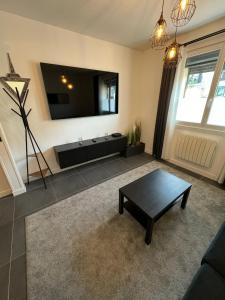 ein Wohnzimmer mit einem TV und einem Couchtisch in der Unterkunft Duplex avec extérieur privatif proche Paris/CDG in Livry-Gargan