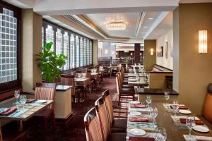 un ristorante con tavoli lunghi, sedie e finestre di Sheraton Hamilton Hotel a Hamilton