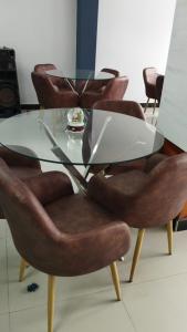 HOTEL VIP 46 SSQS في Bagua Grande: طاولة طعام زجاجية مع كراسي جلدية حولها
