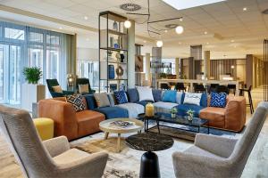 a living room with a blue couch and chairs at Courtyard by Marriott Schwerin in Schwerin