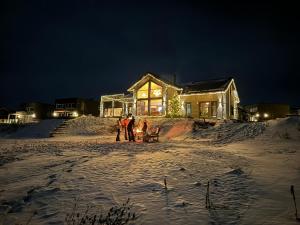 un grupo de personas de pie en la nieve frente a una casa en Lakefront Villa, exclusive leisure property near Vrådal Golf, Straand Summerland & Panorama Ski center en Vradal