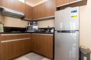 a stainless steel refrigerator in a kitchen with wooden cabinets at The Radiance Manila Bay Condo unit in Manila