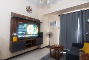 a living room with a tv and a couch and a clock at The Radiance Manila Bay Condo unit in Manila