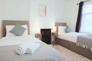 1 dormitorio con 2 camas con sábanas blancas y chimenea en Town Centre House with parking, Wi-Fi, en Stafford