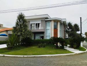 a large house with palm trees in front of it at Casa alto padrão, Jd. Acapulco in Guarujá