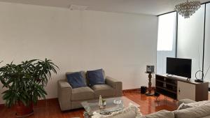 a living room with a couch and a tv at Habitación cerca a los Pantanos de Villa in Lima