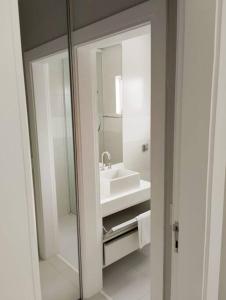 a white bathroom with a sink and a mirror at Casa alto padrão, Jd. Acapulco in Guarujá