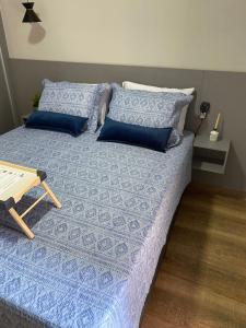 a bed with blue sheets and blue pillows at Apartamento Flat Palladium in São Vicente