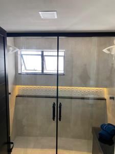 y baño con ducha y puerta de cristal. en Apartamento Flat Palladium en São Vicente