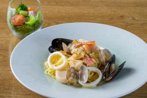 a plate of pasta with shrimp and mussels and a salad at Hotel Edel Warme in Furano