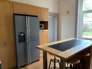 a kitchen with a stainless steel refrigerator and a table at Grande maison familiale, 5 chambres, jardin, proche 24 Heures du Mans et abbaye de Solesmes. - FR-1-410-427 in Juigné-sur-Sarthe +17 photos