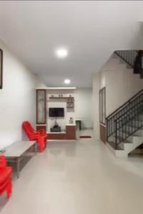 a living room with a staircase and red chairs at VILLA BRASTAGI SINABUNG VIEW in Berastagi