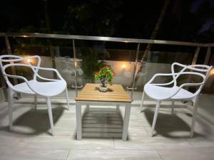 three white chairs and a table with a vase with flowers at The Echelon Suite in Kingston