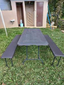 une table de pique-nique et deux bancs dans une cour dans l'établissement Mt Apo View Creekside Whole house with Pool by Creek Cowboys Cottage, à Digos