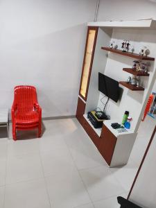 ein Wohnzimmer mit einem roten Stuhl und einem TV in der Unterkunft VILLA BRASTAGI SINABUNG VIEW in Berastagi