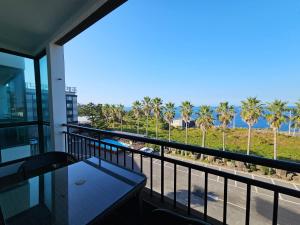 uma varanda com vista para o oceano e palmeiras em Sea Cliff Hotel Jeju em Jeju
